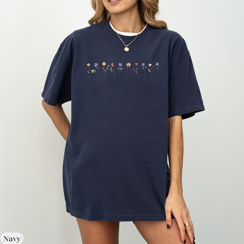 Op de afbeelding: Een oversized navyblauw t-shirt met een rij geborduurde bloemen in verschillende kleuren.