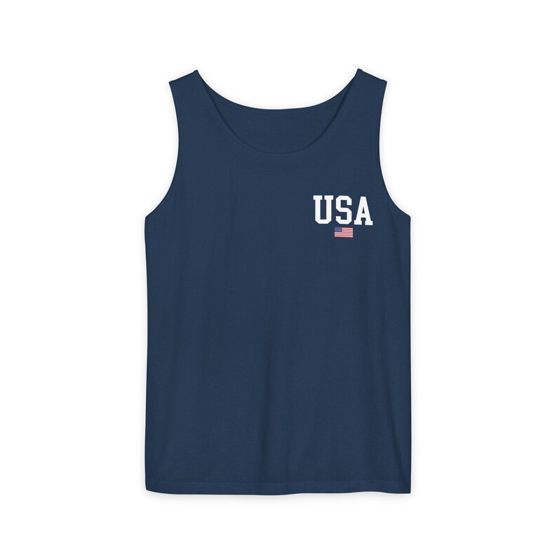 May include: Navy blue tank top with the word "USA" in white block letters and a small American flag graphic. The sleeveless shirt is made of a soft material.