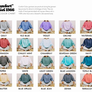 May include: Color chart showing 15 different colors of Comfort Colors 1566 sweatshirts. The sweatshirts are laid out in rows of five, with each sweatshirt folded and sitting on a light brown surface. The colors include gray, flo blue, violet, orchid, watermelon, crimson, chalky mint, chambray, seafoam green, navy, pepper, white, light green, blue lagoon, topaz blue, butter, blue spruce, blue jean, denim, and terracotta.