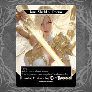 May include: A trading card featuring "Iona, Shield of Emeria." The artwork depicts a blonde-haired figure in white and gold armor, holding a glowing sword. The card includes text describing its abilities and stats.