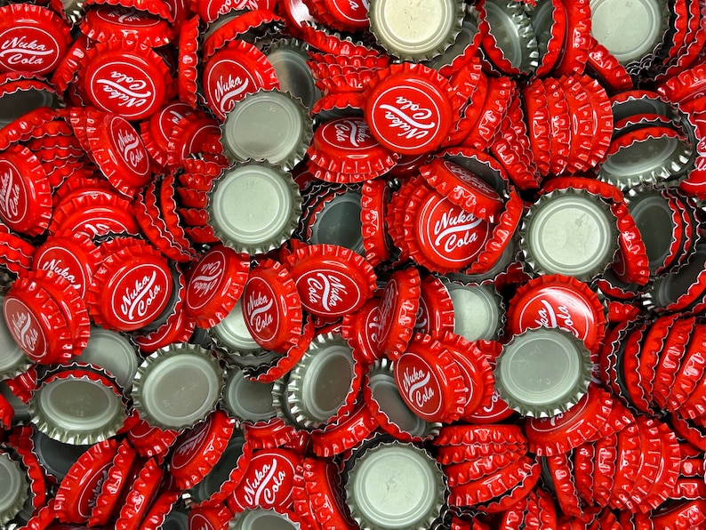 May include: A large pile of red bottle caps with the words "Nuka Cola" printed on them.