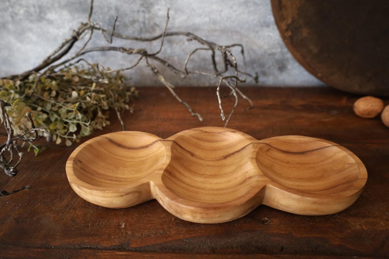 May include: A wooden serving tray with three separate bowls. The tray is made of light brown wood with a natural grain pattern. The bowls are rounded and have a slightly raised lip.