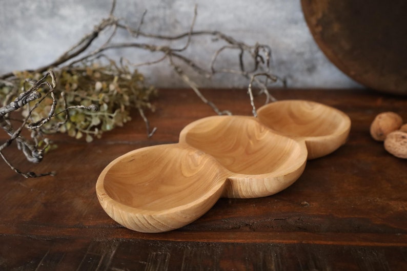 May include: A wooden serving tray with three separate bowls. The tray is made of light brown wood and has a natural finish.