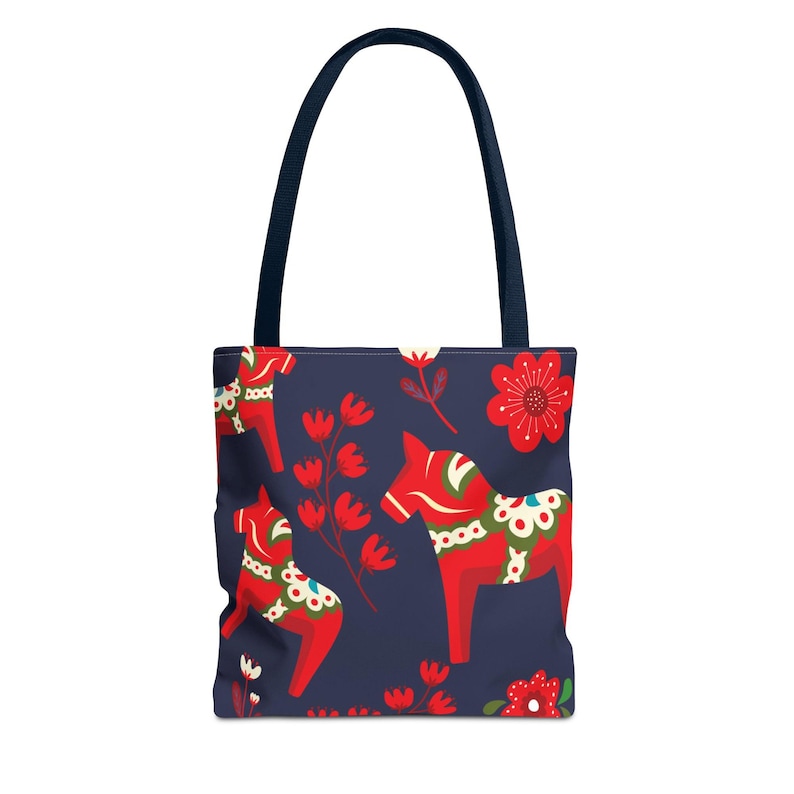 May include: A blue tote bag with a pattern of red and white Dala horses and red flowers. The bag has two navy blue handles.