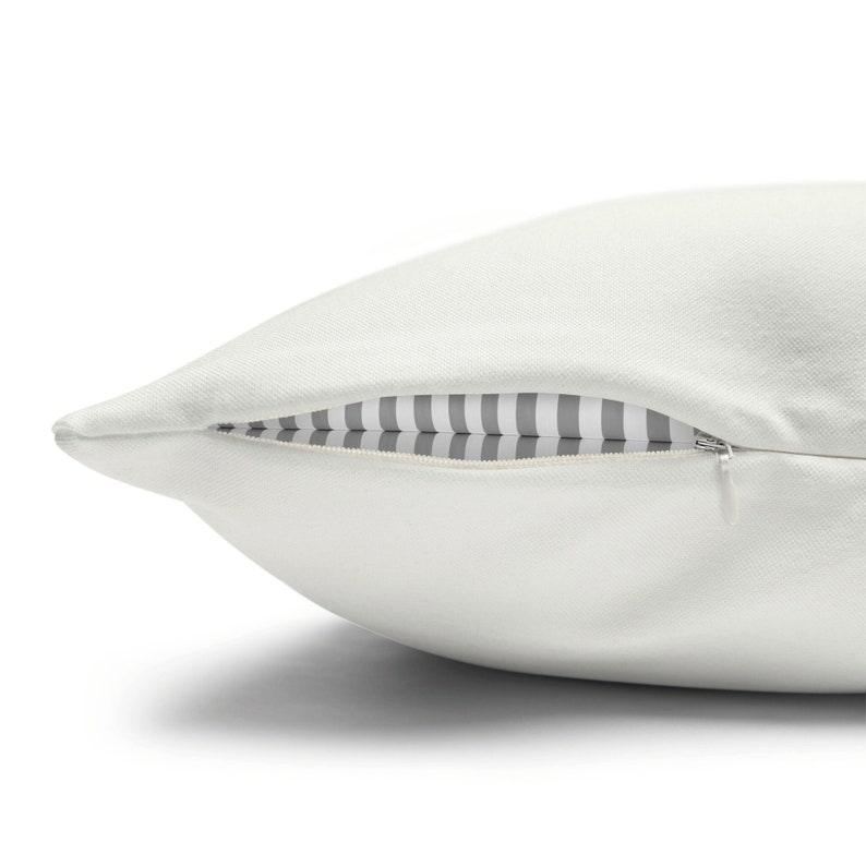 May include: A white pillow with a zipper closure. The zipper is open, revealing a gray and white striped fabric lining.