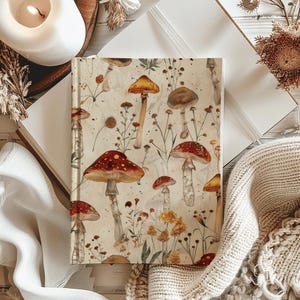 Può includere: Un diario color crema con un motivo a forma di fungo e fiori. I funghi sono rossi e bianchi con steli marroni. I fiori sono gialli e verdi.