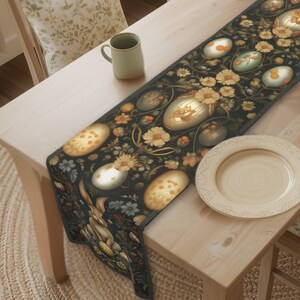 May include: A dining table set with a black floral table runner featuring egg and flower designs. The table is set with plates, mugs, and chairs. A fireplace and window are in the background.