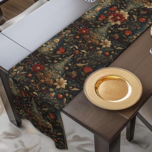 May include: A dining table set for a meal, featuring a dark floral patterned table runner. The table is set with gold-rimmed wine glasses, a gold plate, and a bowl of red flowers. Dark wooden chairs surround the table, creating a warm, inviting atmosphere.