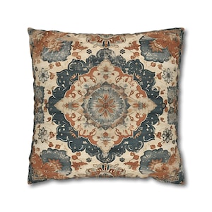 May include: A square throw pillow featuring a symmetrical, intricate medallion pattern in shades of muted rust orange, deep slate blue, and cream. The design includes floral and geometric motifs arranged in a repeating, centered layout.