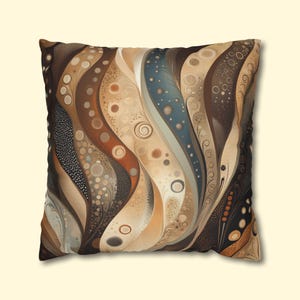 May include: Square decorative pillow with an abstract design. The pillow features a pattern of flowing, vertical lines in shades of brown, beige, and blue. The design includes circles and dots, creating a textured appearance. The pillow has a dark brown border.