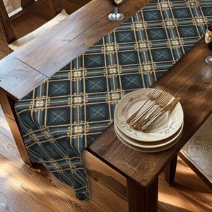 May include: A blue and brown plaid table runner with a decorative grid pattern featuring cream-colored accents. The runner is draped over a wooden table, which also holds a stack of white ceramic plates, two silver forks, and a silver knife.