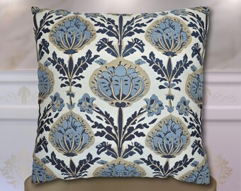 May include: A square throw pillow featuring a repeating floral pattern in shades of light blue, dark navy blue, and beige on an off-white background. The design consists of stylized, symmetrical flower blossoms and leafy stems arranged in a grid.