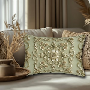 May include: A rectangular throw pillow featuring a pale sage green base with an intricate, raised gold-toned floral and scrollwork pattern. The design consists of a central flower surrounded by symmetrical botanical motifs and ornate filigree.