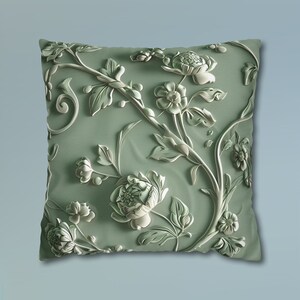 May include: A green throw pillow with an embossed floral design. The pillow features a white floral pattern with intricate details.