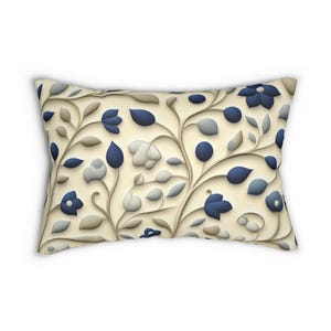May include: A rectangular throw pillow featuring a cream-colored background with a repeating pattern of stylized vines, leaves, and flowers in shades of navy blue, light gray, and beige. The design has a layered, dimensional appearance.