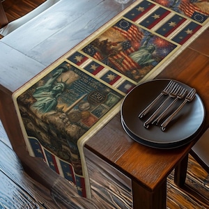 May include: A patriotic table runner featuring the Statue of Liberty, American flags, and historical imagery. The runner has a beige border and is decorated with red, white, and blue stars and stripes. A black plate with four forks rests on a wooden table.