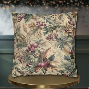 May include: A square throw cushion featuring a botanical print on a cream background. The pattern displays clusters of purple berries, green and brown foliage, and muted floral elements arranged in a dense, repeating design across the fabric.