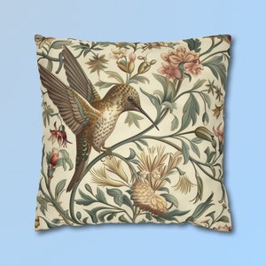 May include: A cream-coloured throw pillow featuring a detailed illustration of a hummingbird perched on a branch with green leaves and pink flowers.