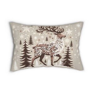 May include: Rectangular cushion with a festive reindeer design. The reindeer is depicted in brown and white with detailed patterns. The background is a light beige, featuring stars, snowflakes, and fir trees. A winter-themed decorative item for the home.