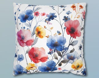May include: A square throw pillow featuring a white background with a watercolor-style floral pattern. The design includes various flowers in shades of blue, red, pink, and yellow, connected by thin, dark stems and delicate, light gray foliage.