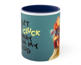 May include: A blue and white ceramic mug with a teal background and a cartoon chicken wearing glasses. The text on the mug reads "Get the Cluck Away from my Mug".