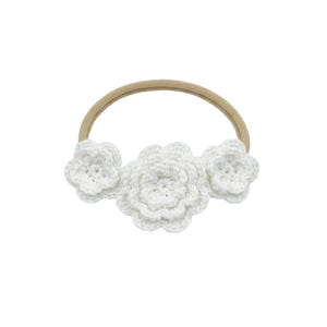 May include: A white crochet headband featuring three flower accents. The flowers are made of a soft, textured yarn and are attached to a neutral-colored elastic band. The headband is designed for babies and young children.