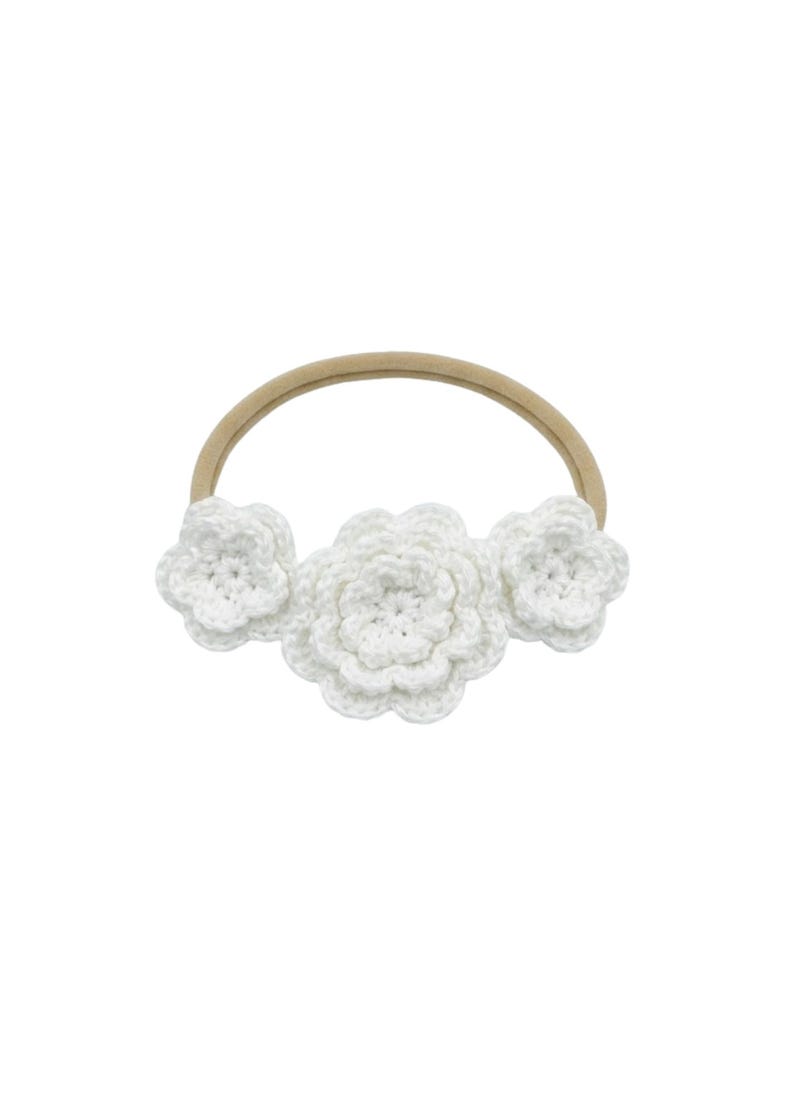 May include: A white crochet headband featuring three flower accents. The flowers are made of a soft, textured yarn and are attached to a neutral-colored elastic band. The headband is designed for babies and young children.