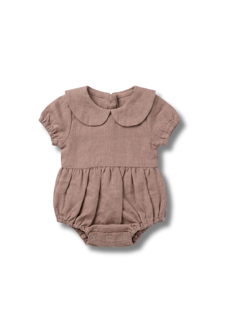 Puede incluir: Un pelele para beb&eacute; de color rosa empolvado, con cuello redondo y mangas cortas. El pelele presenta una cintura fruncida y cierres de presi&oacute;n en la parte inferior. Fabricado en tejido suave y texturizado, est&aacute; dise&ntilde;ado para la comodidad y el estilo.