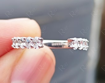 Pode incluir: Um anel aberto de tom prateado com duas filas de pequenas pedras transparentes facetadas engastadas nas extremidades da banda. A banda tem um acabamento metálico polido e uma abertura no centro, exibindo um design simétrico e limpo.