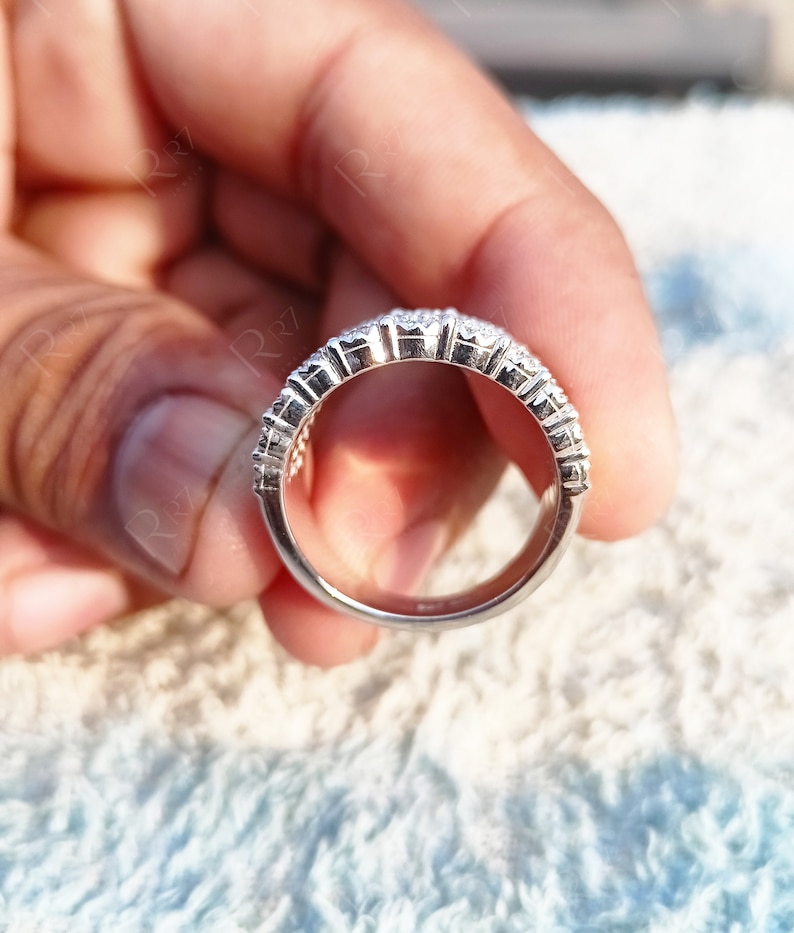 May include: A silver ring with a row of small, clear stones set in a band.