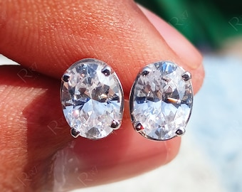 May include: A pair of oval-shaped earrings with clear cubic zirconia stones set in silver.