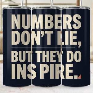 May include: A dark navy blue cylindrical tumbler with a metal straw. The tumbler features the cream-coloured text "NUMBERS DON'T LIE, BUT THEY DO INSPIRE..." with a small orange bar graph icon at the end of the final word on the lower right side.
