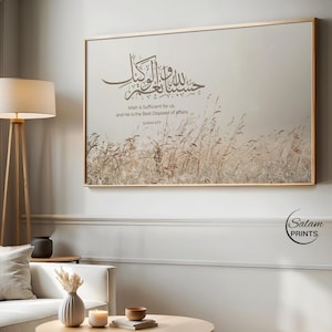 Puede incluir: Una impresión enmarcada con un borde dorado muestra caligrafía árabe y texto en inglés: "Allah es suficiente para nosotros, y Él es el mejor administrador de los asuntos". La obra de arte presenta un fondo beige con un campo de hierba alta.
