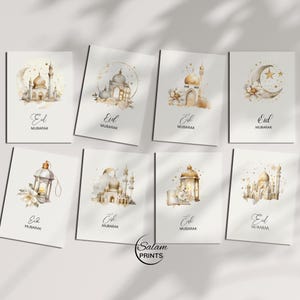 May include: A collection of Eid Mubarak greeting cards. Each card features watercolor illustrations of mosques, lanterns, and crescent moons in gold and beige tones. The cards have the words "Eid Mubarak" in elegant script.