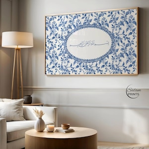 May include: A framed artwork with a blue and white floral design. The artwork has an oval centre with Arabic calligraphy. The frame is a light wood colour, suitable for home decor.