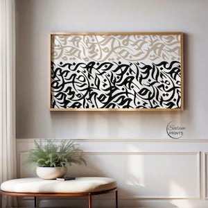 May include: A framed artwork with abstract calligraphy in black and beige on a white background. The artwork is split into two horizontal sections, with beige at the top and black at the bottom. The frame is a light wood colour.