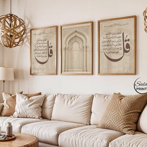 May include: A set of three framed wall art prints featuring beige backgrounds with dark brown Arabic calligraphy and an architectural arch illustration. The prints are displayed in light wood frames, showcasing intricate script and detailed designs.