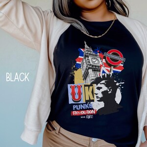May include: Black t-shirt with a graphic design featuring a stylized image of Big Ben, the London Underground sign, and the text "UK PUNKS REVOLUTION >>> 2024".