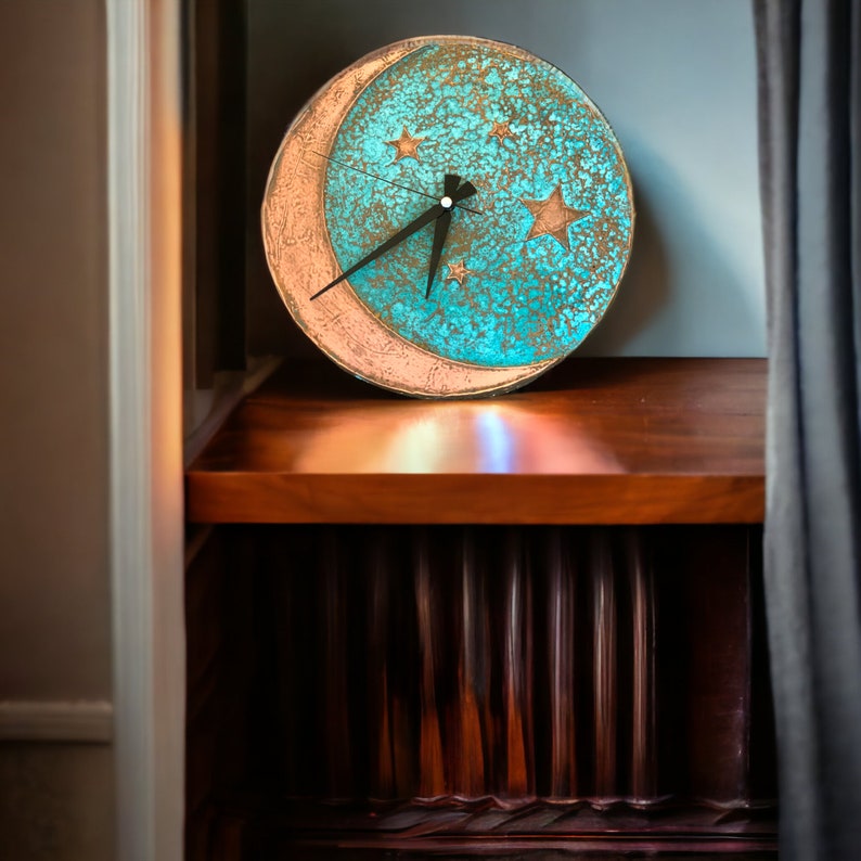 May include: A turquoise and gold moon-shaped clock with black hands and gold stars on a wooden shelf.