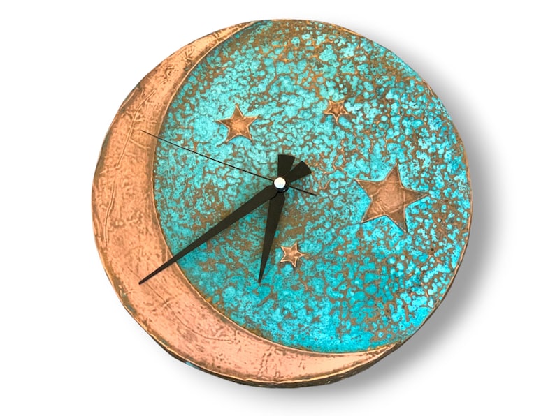 May include: A turquoise blue and copper colored clock with a crescent moon and stars design. The clock has black hands and a white face.