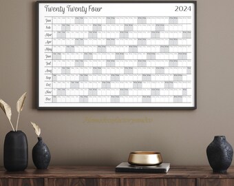 May include: A black and white calendar with the title "Twenty Twenty Four" and the year "2024" printed on it. The calendar is divided into months, with each month having a grid of days. The calendar is hanging on a wall.