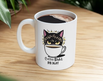 Könnte beinhalten: Weiße Keramik-Kaffeetasse mit einer schwarzen Katzenillustration. Die Katze schaut aus einer Kaffeetasse mit dem Text "Coffee Right Meow!" darunter.