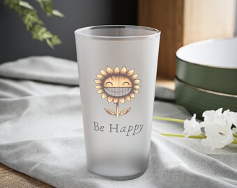 Könnte beinhalten: Ein gefrostetes Glas mit einem lächelnden Sonnenblumen-Motiv und dem Text "Be Happy".