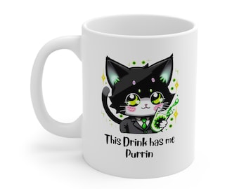 Könnte beinhalten: Eine weiße Keramiktasse mit einer schwarzen Katze, die einen grünen Anzug trägt und ein grünes Getränk hält. Der Text auf der Tasse lautet "This Drink has me Purrin".