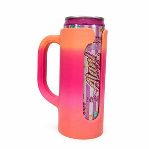 May include: A pink and orange gradient can cooler with a handle, holding a can of energy drink. The cooler has a cutout to display the can's label, and the handle is designed for easy gripping. The can is purple and white.