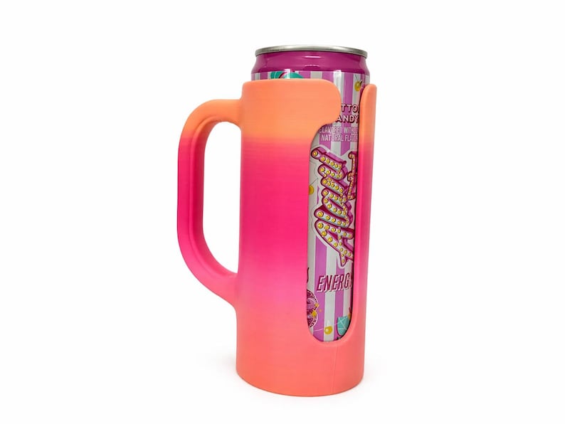 May include: A pink and orange gradient can cooler with a handle, holding a can of energy drink. The cooler has a cutout to display the can's label, and the handle is designed for easy gripping. The can is purple and white.