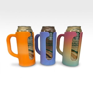 May include: Three colorful can holders in orange, blue, and a gradient of pink, orange, and green. Each holder has a mug-like handle and a cutout to display the can's label. The cans are labeled "Starbucks Doubleshot Energy".