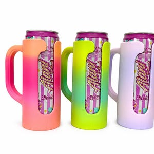 May include: Three colorful can coolers in pink, green, and lavender, each holding a can of energy drink. The coolers have a handle and a cutout to display the can's label. The energy drink cans have a purple and white striped design.
