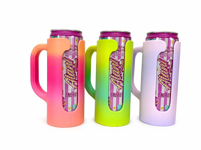 May include: Three colorful can coolers in pink, green, and lavender, each holding a can of energy drink. The coolers have a handle and a cutout to display the can's label. The energy drink cans have a purple and white striped design.