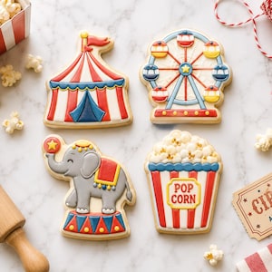 May include: Four decorated sugar cookies featuring circus themes: a red and white striped tent, a blue and yellow ferris wheel, a gray elephant balancing a ball, and a red and white striped popcorn bucket with the text POP CORN printed on it.